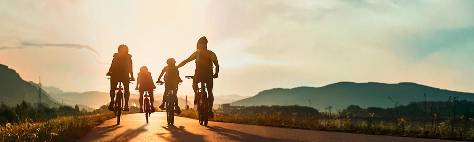 family riding bikes into sunset